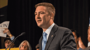 LP Chair Nicholas Sarwark speaking at microphone, wearing suit & tie (color photo)