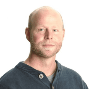 Clif Ingram headshot, white background, dark grey knit shirt, looking at camera, a hint of a smile (color photo)