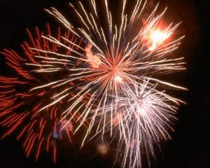 image of several layered fireworks bursts in night sky (color photo)